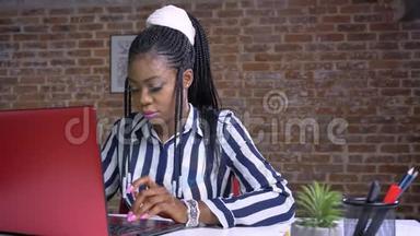 可爱的非洲成年女商人一边坐在桌子旁<strong>专注</strong>而<strong>专注</strong>地工作在她的笔记本电脑上